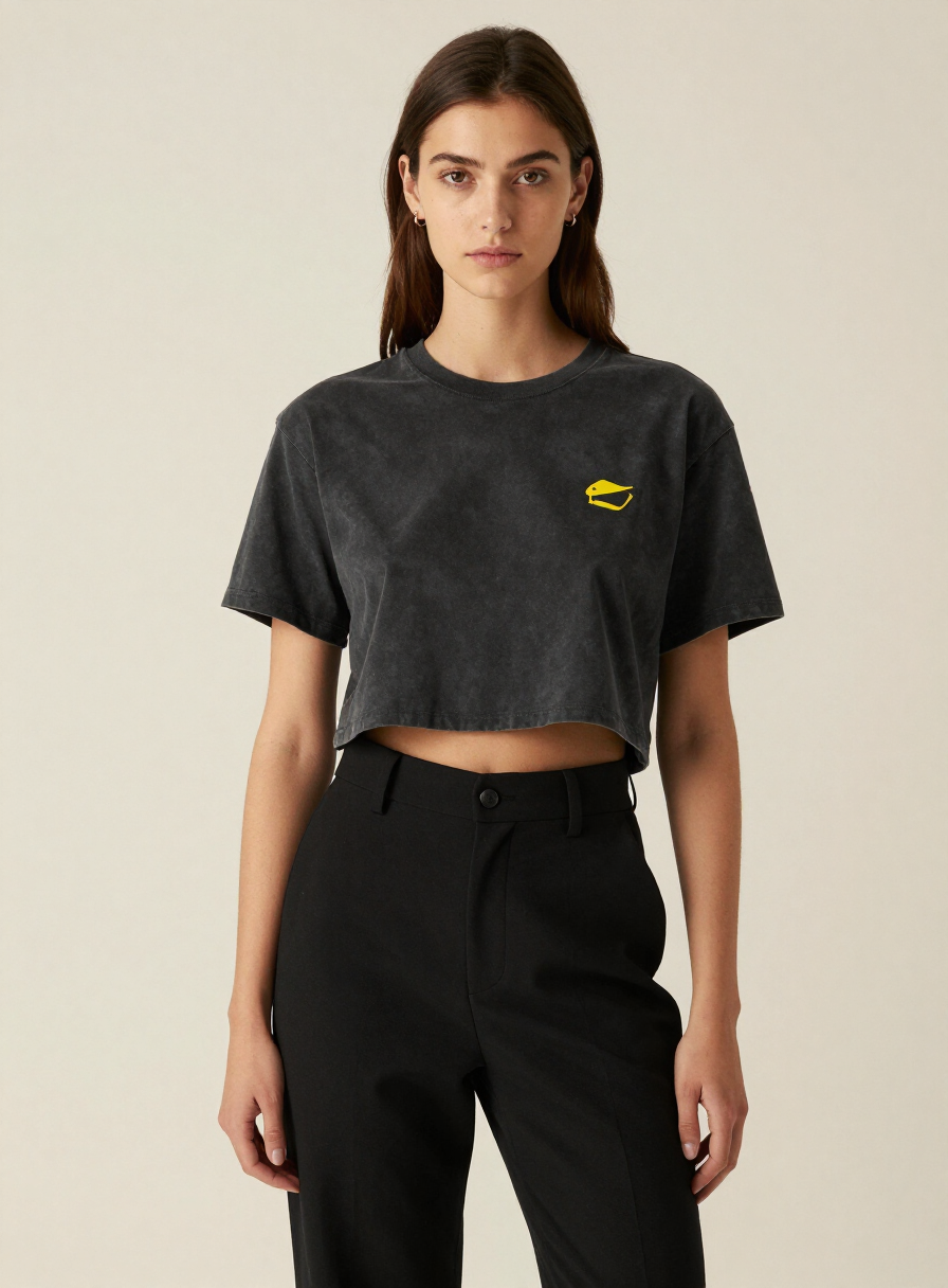 Model wearing a cropped boxy t-shirt in faded black with a small yellow chest print