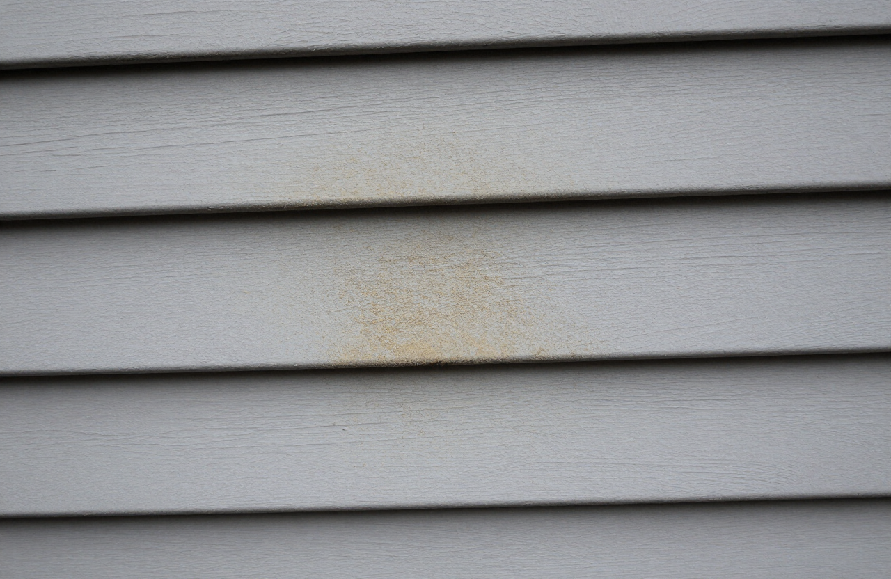 Close-up of pollution damage and traffic grime on exterior siding near Route 17 in Hasbrouck Heights NJ