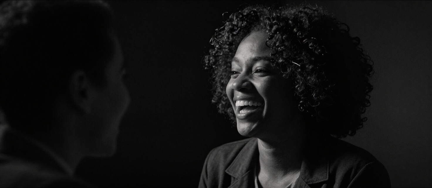 A woman laughing mid-conversation in a dark studio