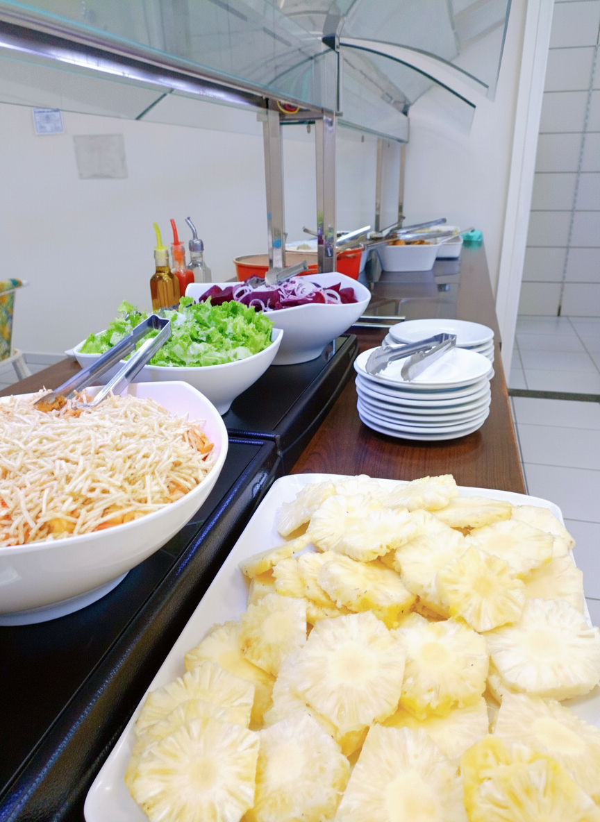 Buffet de saladas, beterraba e abacaxi fatiado em linha de serviço